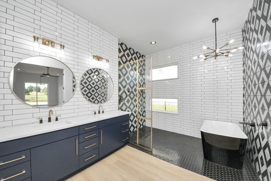 A spa-inspired primary en suite featuring a double quartz vanity with custom cabinetry, designer lighting, a frameless walk-in shower with bold geometric tile, and a freestanding soaking tub for a true resort-style retreat. A spa-inspired primary en suite featuring a double quartz vanity with custom cabinetry, designer lighting, a frameless walk-in shower with bold geometric tile, and a freestanding soaking tub for a true resort-style retreat.