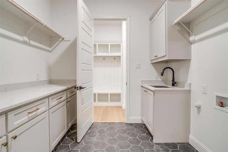 Laundry area with sink, cabinets, dark tile patterned floors, and hookup for a washing machine