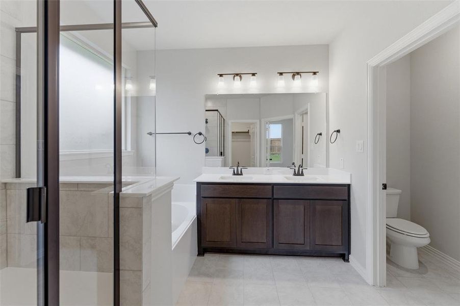 Bathroom featuring a dark wood double vanity with white countertops, dual sinks, and matte black fixtures