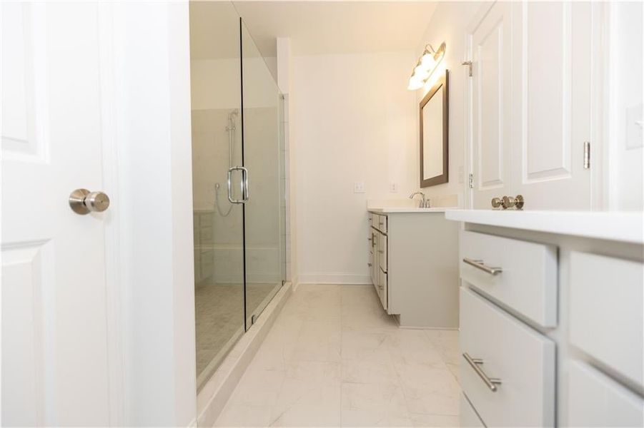 A frameless oversized tile shower offers a bit of luxury in the primary bath. Not actual home. Photos of previously built Stockton plan.