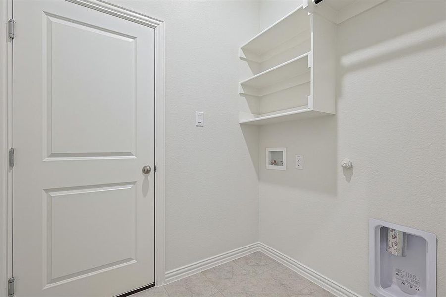 Laundry area featuring washer hookup and light tile patterned floors