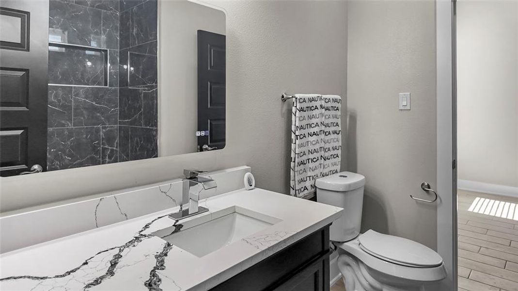 Full bath featuring vanity, a marble finish shower, wood tiled floors, and a textured wall