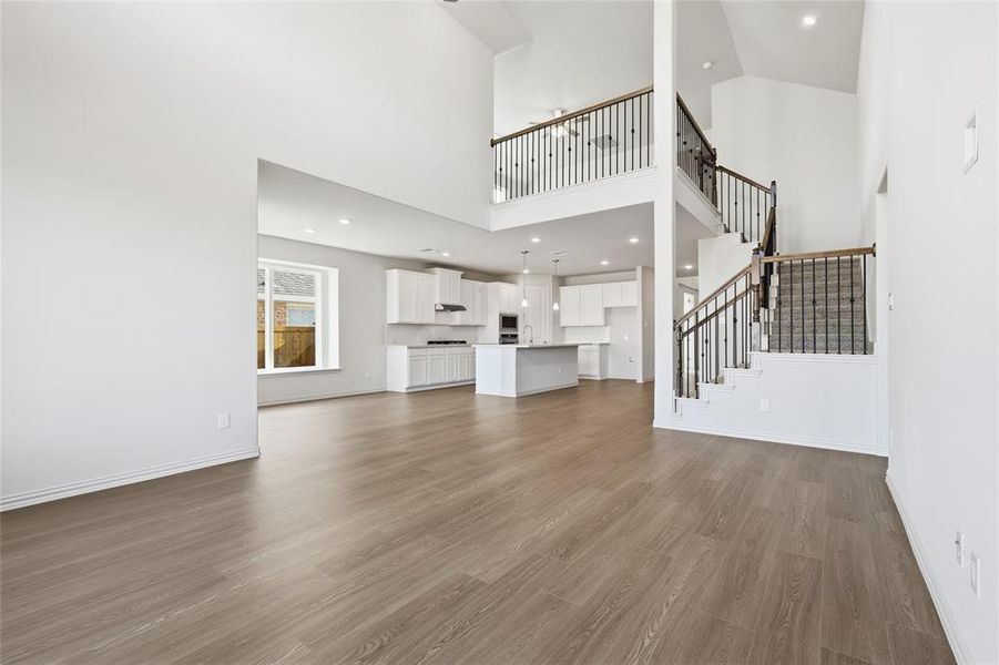 Unfurnished living room featuring dark wood finished floors, stairway, recessed lighting, and a high ceiling Unfurnished living room featuring dark wood finished floors, stairway, recessed lighting, and a high ceiling