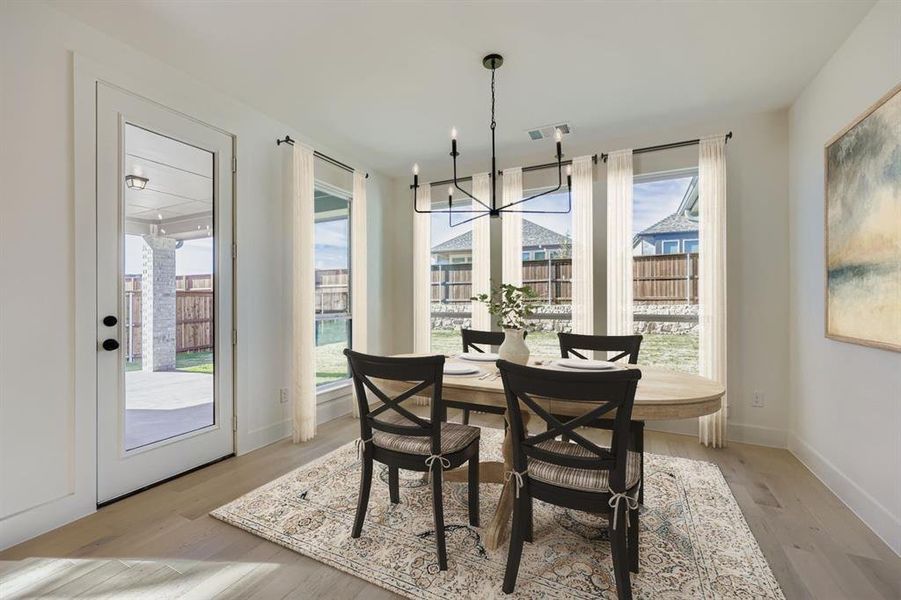Virtually staged photo - Dining space featuring hanging lights and light wood-style floors