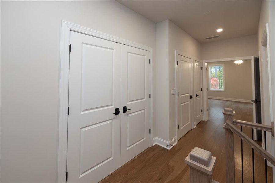 Corridor featuring an upstairs landing, dark wood-style floors, and recessed lighting