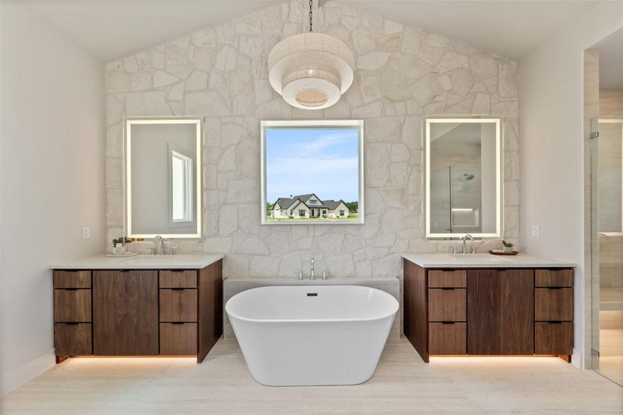 Full bathroom featuring a freestanding tub, two vanities, lofted ceiling, a stall shower, and tile walls