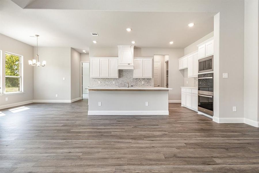 Kitchen with white cabinets, backsplash, an island with sink, and recessed lighting Kitchen with white cabinets, backsplash, an island with sink, and recessed lighting