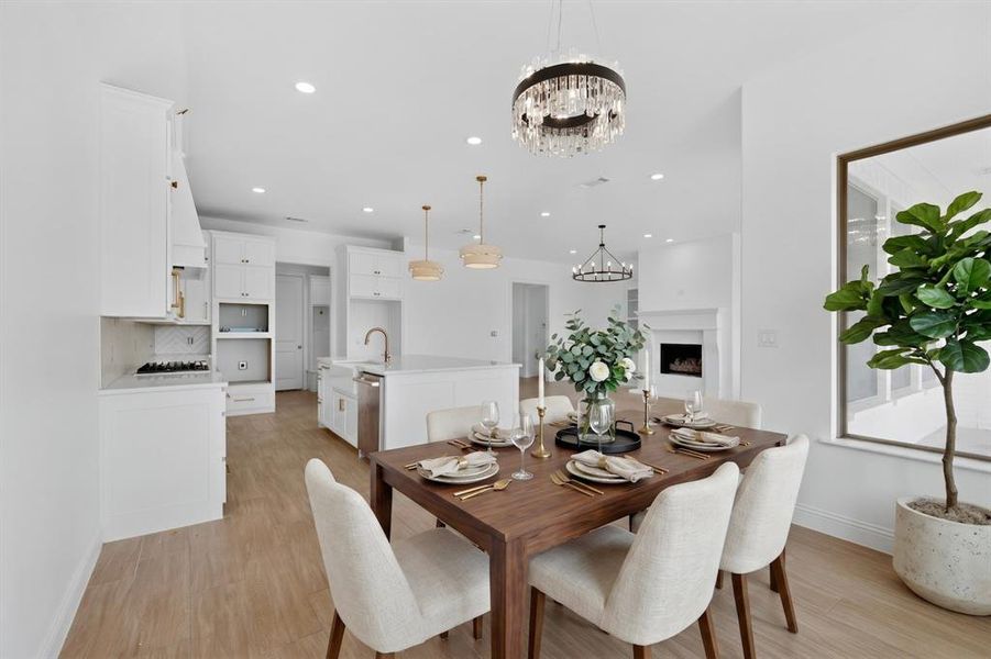 Open-concept dining area featuring a crystal chandelier, wood-finish flooring, and a large window Open-concept dining area featuring a crystal chandelier, wood-finish flooring, and a large window