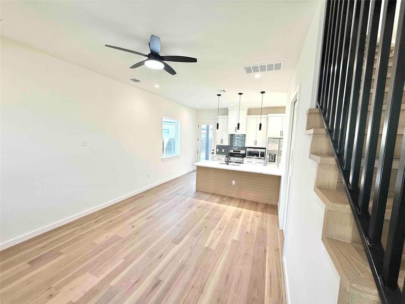 Unfurnished living room featuring light wood-style flooring, stairs, a ceiling fan, and recessed lighting