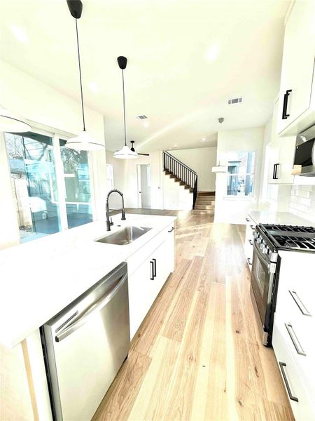 Kitchen featuring white cabinetry, decorative light fixtures, appliances with stainless steel finishes, light wood-style floors, and recessed lighting