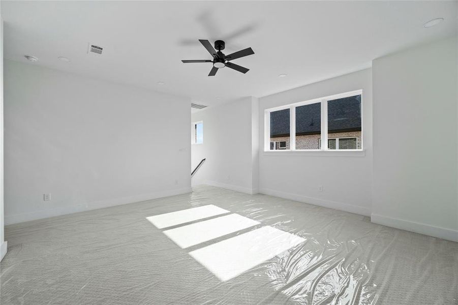 Carpeted empty room with ceiling fan and baseboards