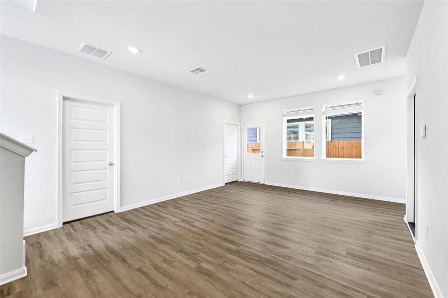 This photo showcases a bright, open living space with wood-style flooring, recessed lighting, and ample natural light from two windows. The room features clean, white walls and multiple doors, offering a modern and versatile layout.Please note: The image is not the actual home; it is a home with the same floor plan in the neighborhood. Finishes may vary. This photo showcases a bright, open living space with wood-style flooring, recessed lighting, and ample natural light from two windows. The room features clean, white walls and multiple doors, offering a modern and versatile layout.Please note: The image is not the actual home; it is a home with the same floor plan in the neighborhood. Finishes may vary.