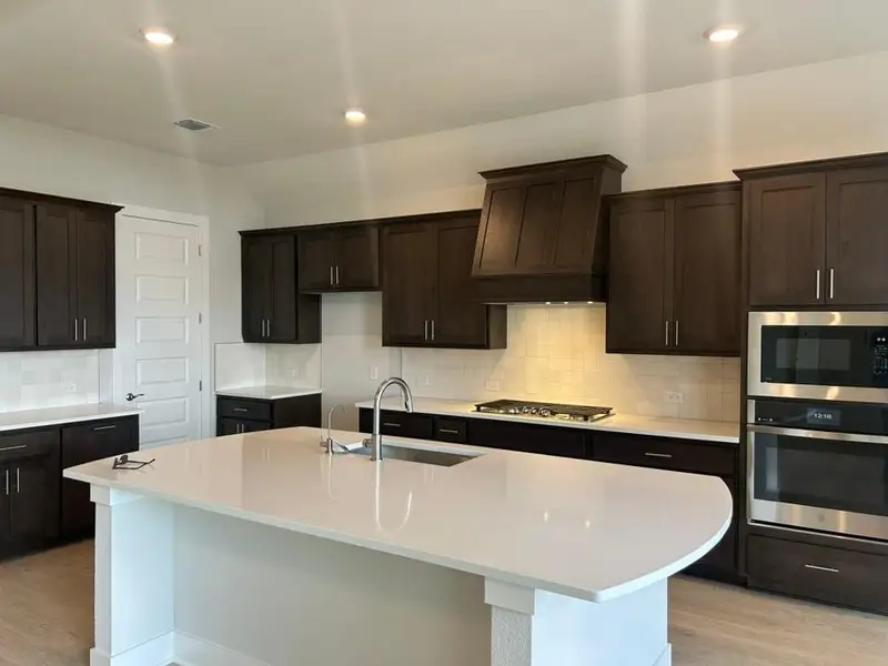 Kitchen with tasteful backsplash, stainless steel appliances, light wood-style floors, dark brown cabinets, and recessed lighting