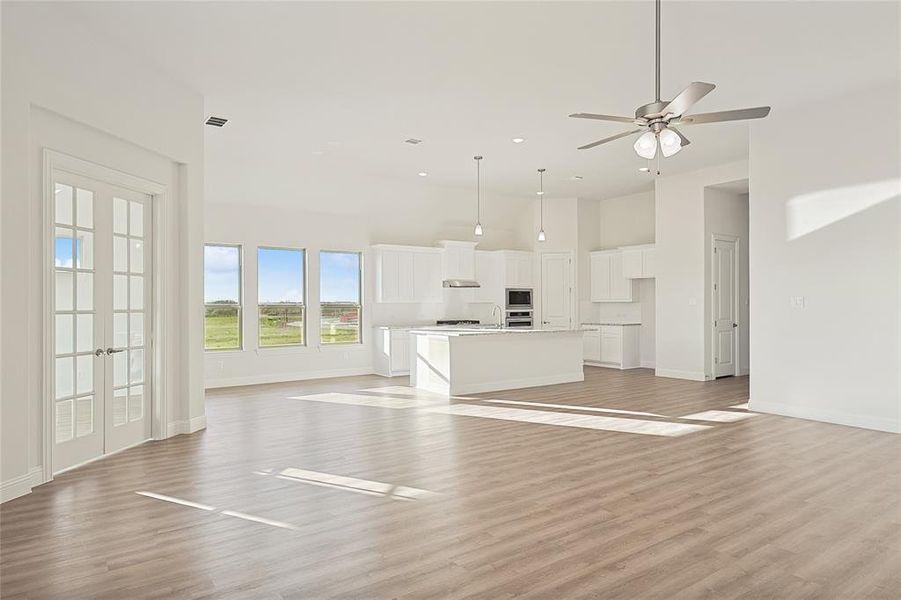 Unfurnished living room with french doors, light hardwood / wood-style flooring, and ceiling fan