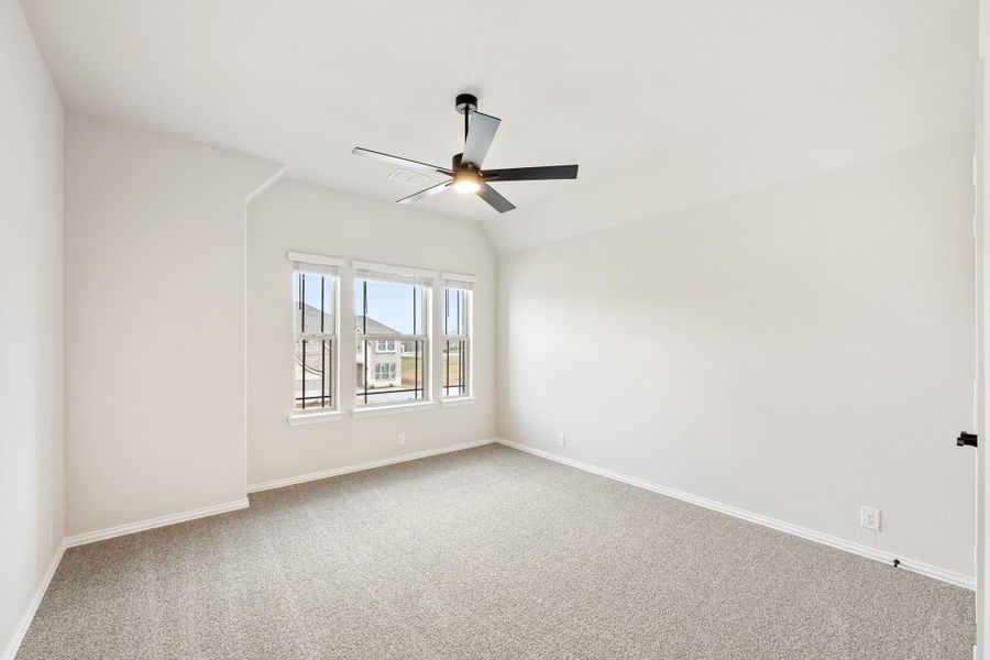 Empty bedroom with vaulted ceiling, ceiling fan, carpet flooring, and triple window Empty bedroom with vaulted ceiling, ceiling fan, carpet flooring, and triple window