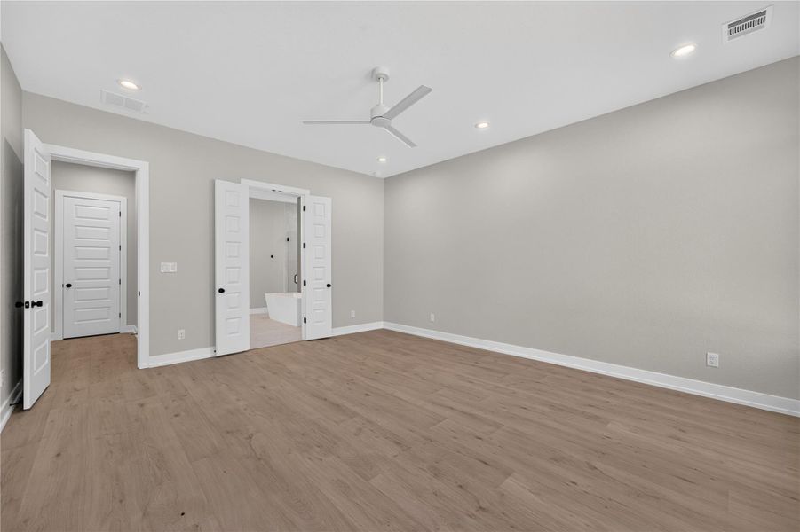 Smooth wood floors and tall ceilings anchor this spacious bedroom suite.