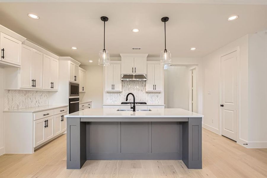 Kitchen with stainless steel appliances, under cabinet range hood, light countertops, white cabinets, and decorative backsplash Kitchen with stainless steel appliances, under cabinet range hood, light countertops, white cabinets, and decorative backsplash