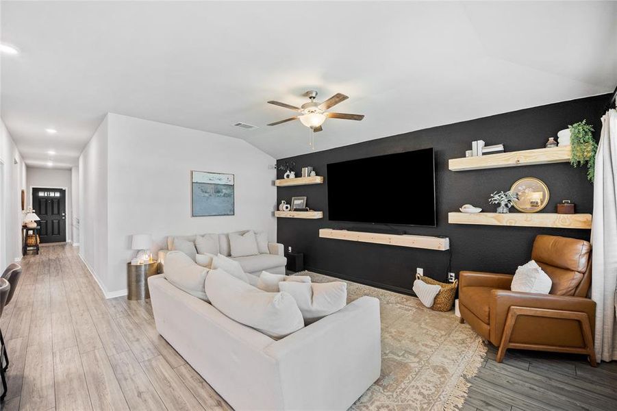 Living area with an accent wall, vaulted ceiling, light wood-style flooring, ceiling fan, and recessed lighting