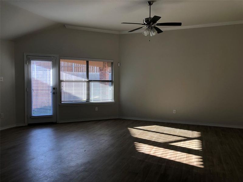 Empty room with dark wood-type flooring, ceiling fan, and a healthy amount of sunlight