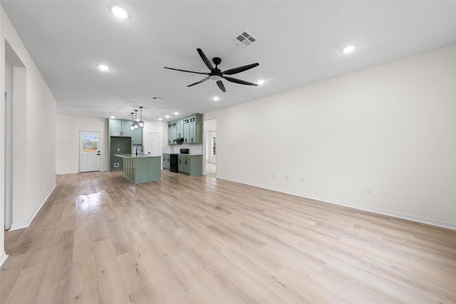 Unfurnished living room with light wood finished floors, recessed lighting, a ceiling fan, and a chandelier