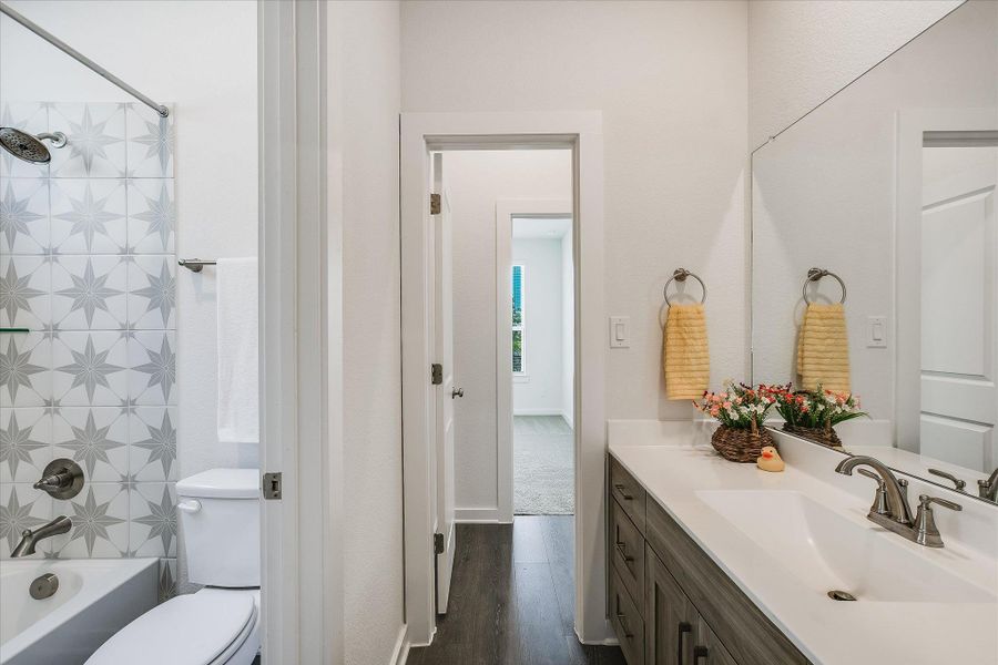 Bathroom featuring a vanity with an integrated sink, a large wall mirror, and wood-finish flooring