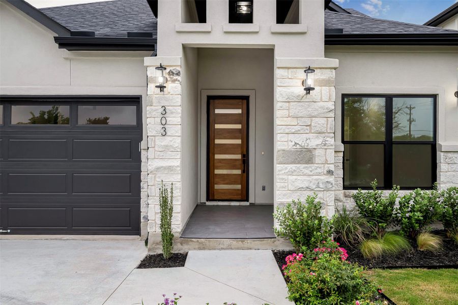 Entrance to the property featuring stone and stucco siding, a shingled roof, and an attached garage. Entrance to the property featuring stone and stucco siding, a shingled roof, and an attached garage.