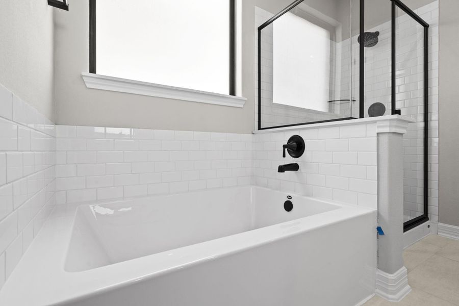 This additional view of your primary bathroom features tile flooring, fresh paint, walk-in shower, a separate garden tub, and a large walk-in closet.