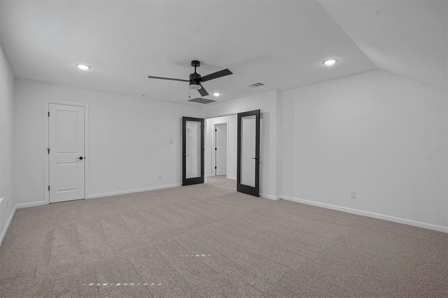 Spare room featuring light carpet, french doors, vaulted ceiling, and ceiling fan