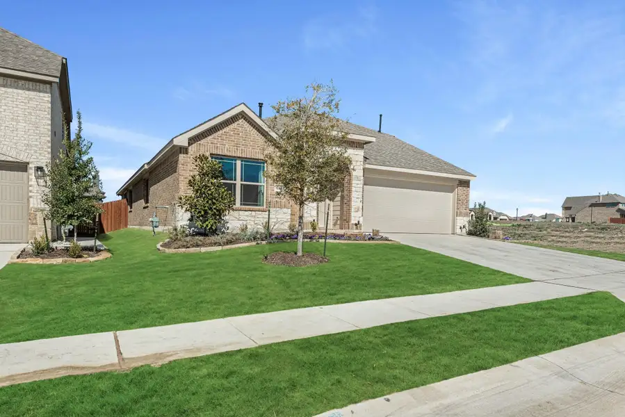 Single-story brick and stone home with two-car garage and landscaped front yard with young trees. Single-story brick and stone home with two-car garage and landscaped front yard with young trees.