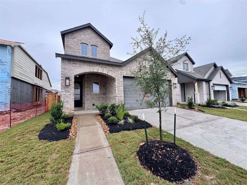 The exterior brick is a warm, earthy greige-tan brick with soft weathered variation and a slightly aged, upscale Texas-traditional look.