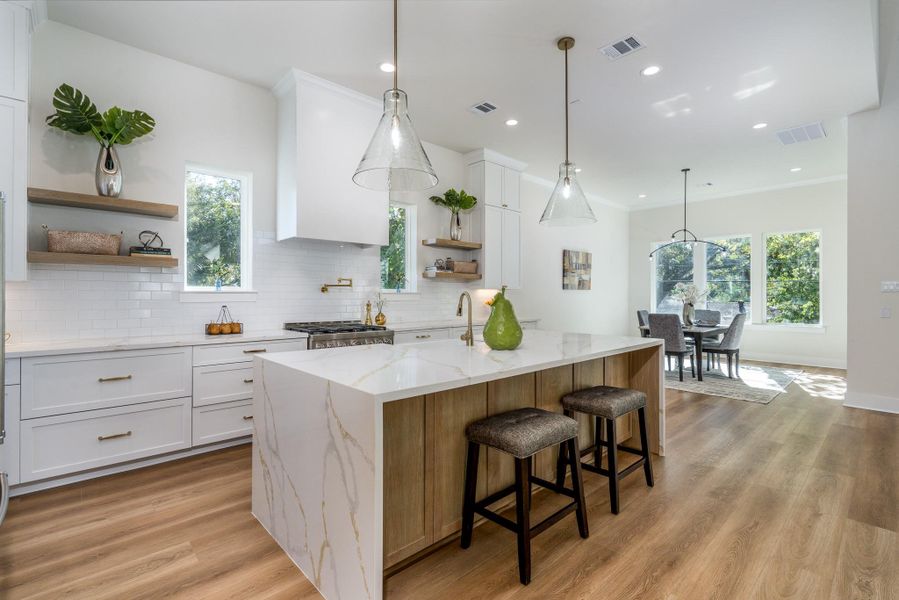 Showcase kitchen with sleek cabinets, gorgeous waterfall island, high-end appliances, and under-cabinet lighting. This open layout flows seamlessly into the living and dining areas for effortless entertaining. Showcase kitchen with sleek cabinets, gorgeous waterfall island, high-end appliances, and under-cabinet lighting. This open layout flows seamlessly into the living and dining areas for effortless entertaining.