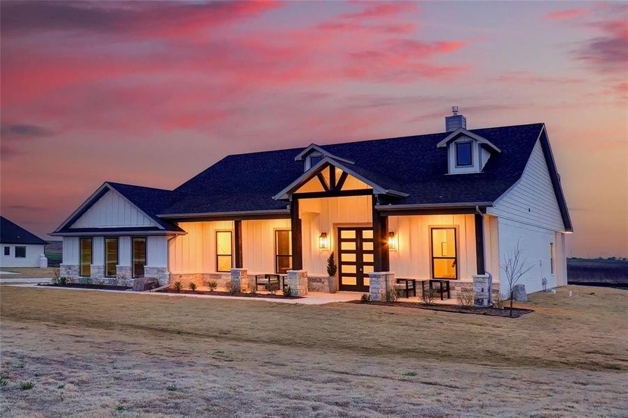 View of front of house with a chimney, stone siding, covered porch, french doors, and board and batten siding