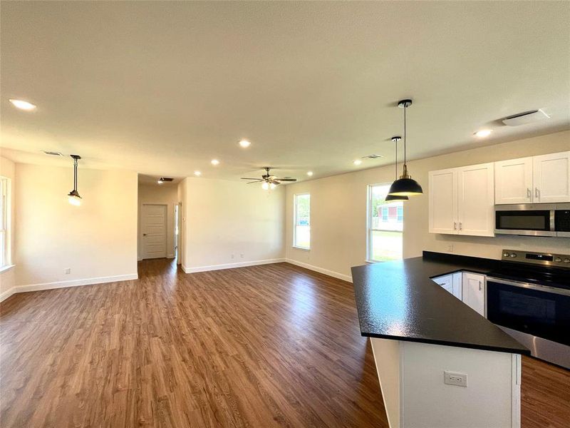 Kitchen with ceiling fan, dark wood-type flooring, white cabinets, decorative light fixtures, and stainless steel appliances