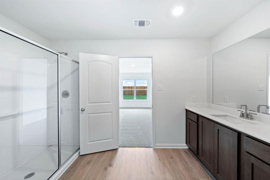 Bathroom with light wood finished floors, vanity, recessed lighting, and a stall shower