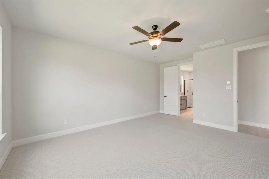 Spacious room featuring light-toned carpeting, a ceiling fan with integrated lighting, and a window with white trim