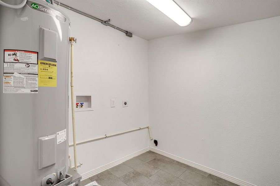 Washroom featuring water heater, hookup for a washer and dryer