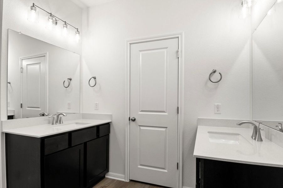 Bathroom featuring two vanities and dark wood-style flooring