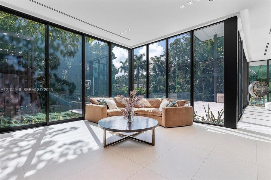 Floor-to-ceiling glass wall panels with black framing, large-format tile flooring, and recessed ceiling lighting