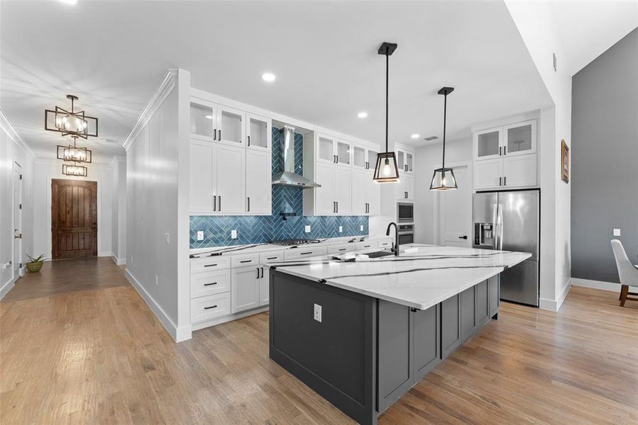 Kitchen with glass insert cabinets, white cabinetry, tasteful backsplash, stainless steel appliances, and pendant lighting Kitchen with glass insert cabinets, white cabinetry, tasteful backsplash, stainless steel appliances, and pendant lighting
