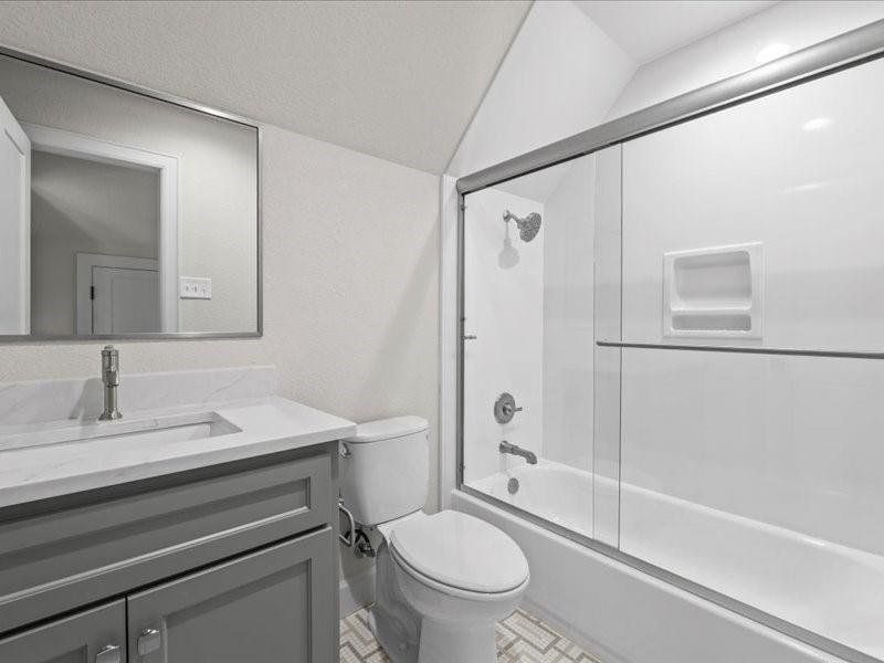 Full bath featuring enclosed tub / shower combo, lofted ceiling, and vanity