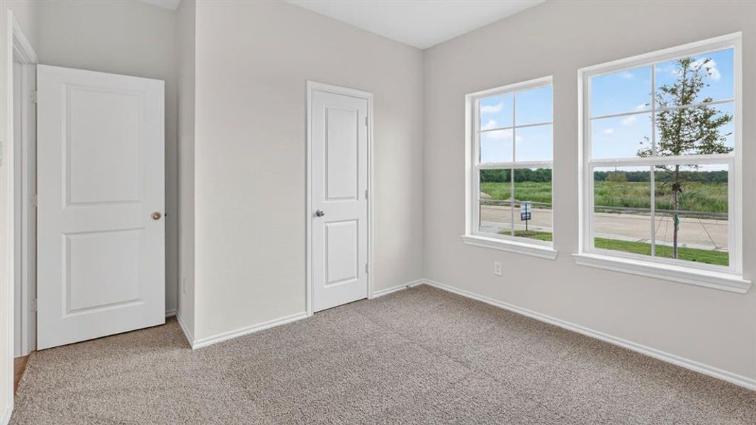 Room featuring two panel interior doors, light gray wall paint, white trim, and gray carpet flooring Room featuring two panel interior doors, light gray wall paint, white trim, and gray carpet flooring