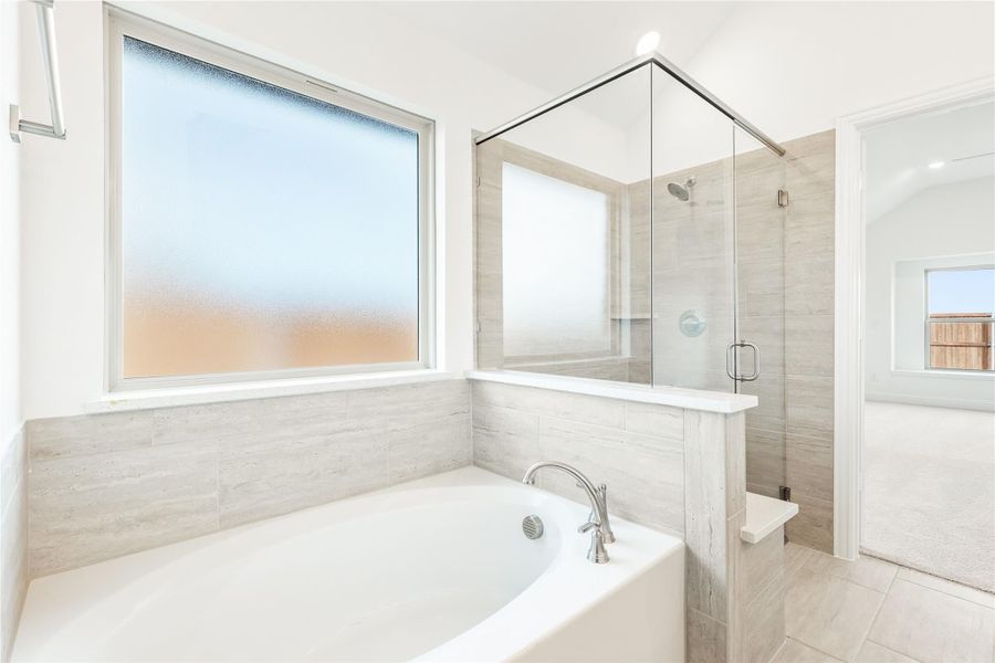 Master bathroom with soaking tub, glass-enclosed shower, and light gray tile walls and floors Master bathroom with soaking tub, glass-enclosed shower, and light gray tile walls and floors