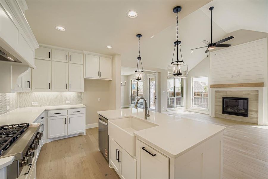 Kitchen with light wood-type flooring, white cabinetry, decorative backsplash, hanging light fixtures, and recessed lighting