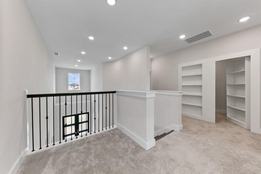 Versatile upstairs landing featuring built-in shelving and a unique hidden space, perfect for storage or a private nook. Overlooking the main living area, this flexible space adds both function and character to the home.