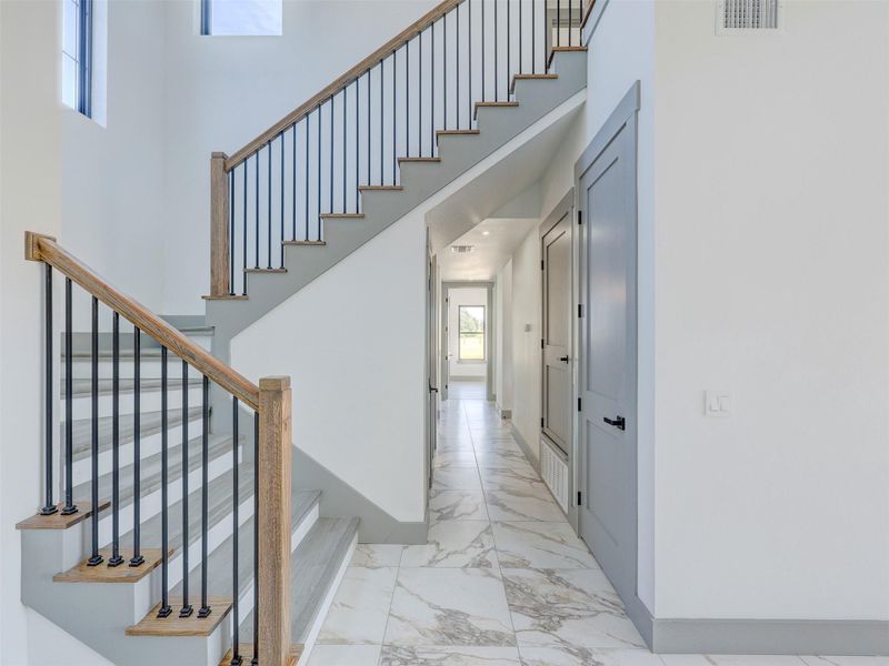 Polished tile flooring and an elegant open-rail staircase anchor this sleek, modern entry hall.