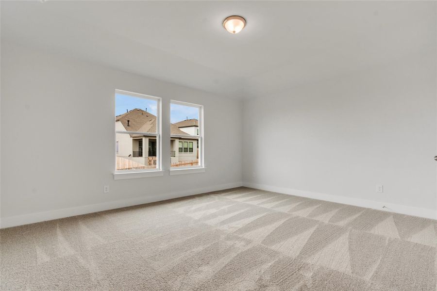 A well-lit, neutral-toned bedroom with clean carpet, awaiting personal touches.