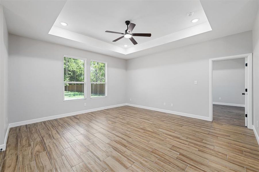 Empty room featuring ceiling fan and a tray ceiling