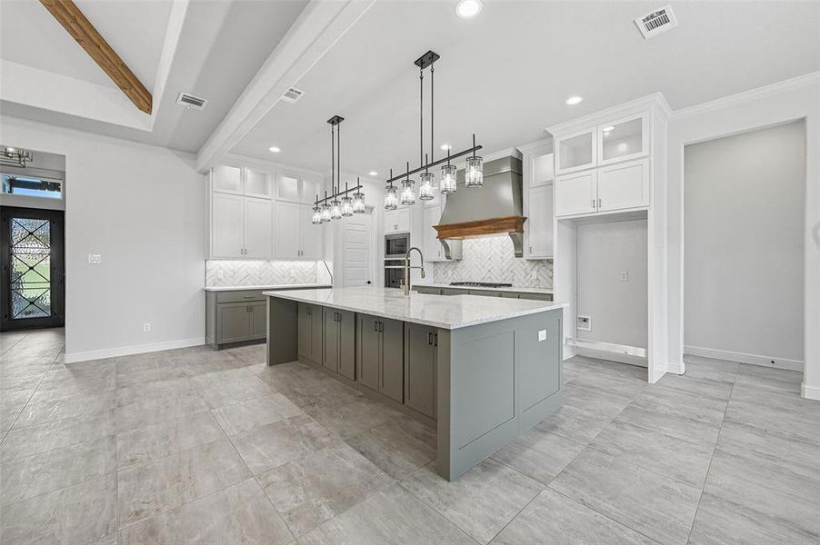 Kitchen with glass insert cabinets, gray cabinetry, a spacious island, tasteful backsplash, and beam ceiling Kitchen with glass insert cabinets, gray cabinetry, a spacious island, tasteful backsplash, and beam ceiling
