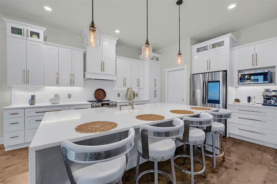 Kitchen with an island with sink, white cabinetry, decorative backsplash, and appliances with stainless steel finishes