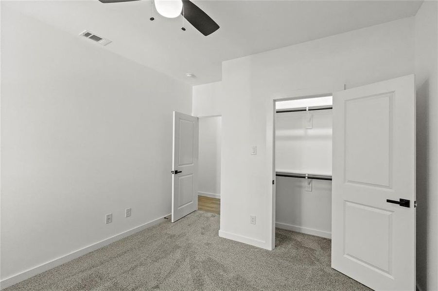 Unfurnished bedroom featuring ceiling fan, a closet, and light carpet